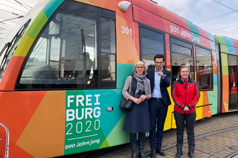 3 Personen vor Straßenbahn in Freiburg