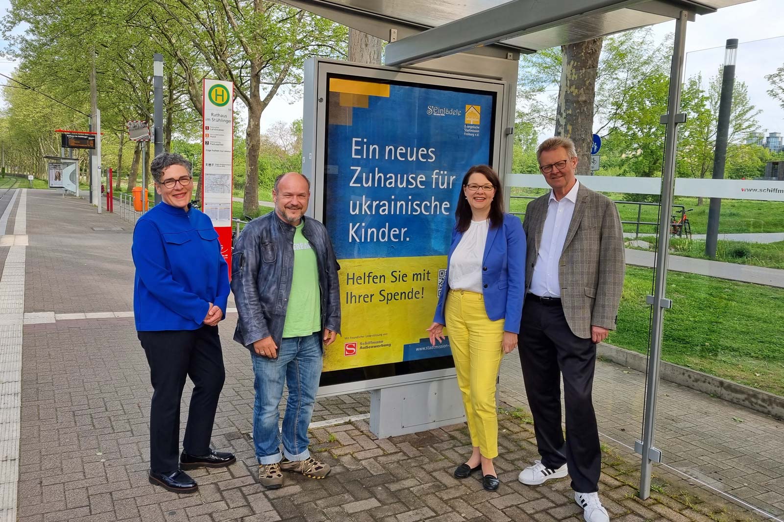 Gespendete Plakataktion Ukraine-Spende an Straßenbahn-Haltstelle in Freiburg mit vier Personen